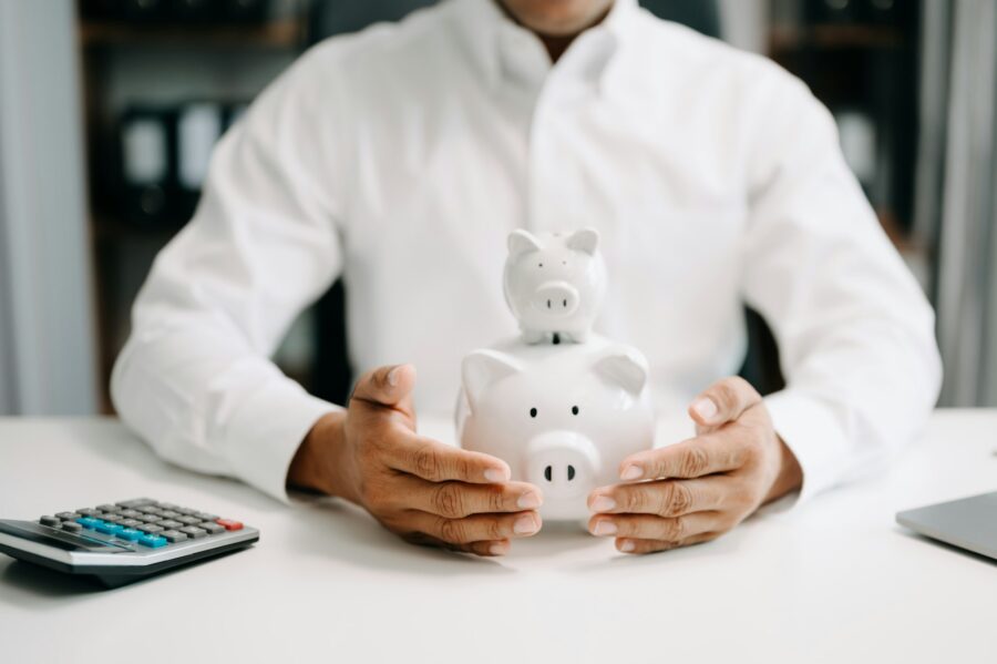 Asian Man are putting coins in a piggy bank for a business that grows for profit and saving money